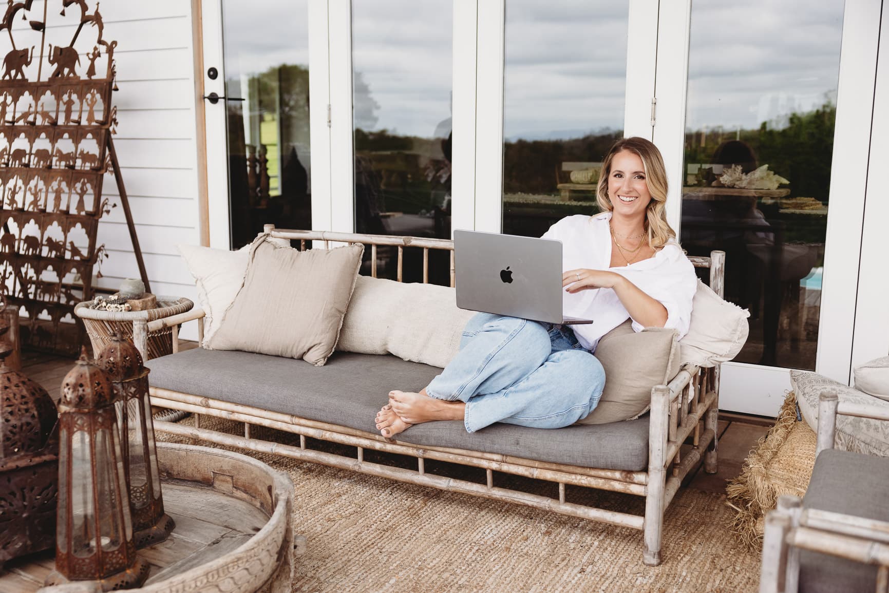 Jess Clark smiling on the couch with her laptop
