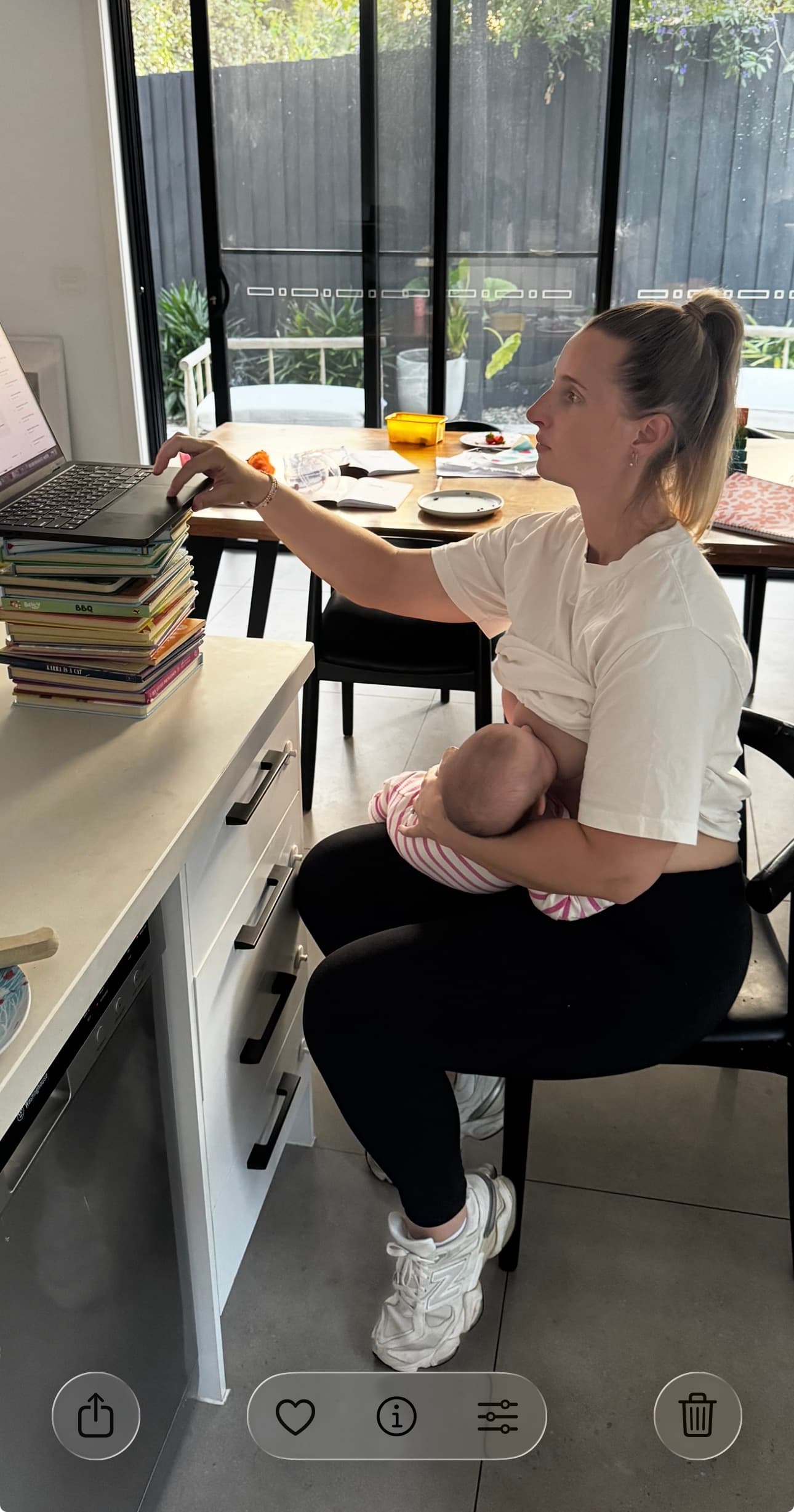 Jess at her dining table, laptop open, breastfeeding Lottie. Building in real life.